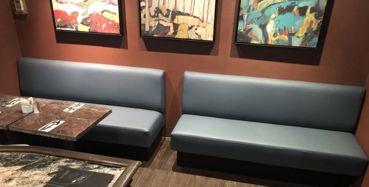 Blue grey vinyl benches with dark bases below three abstract paintings on a terracotta wall