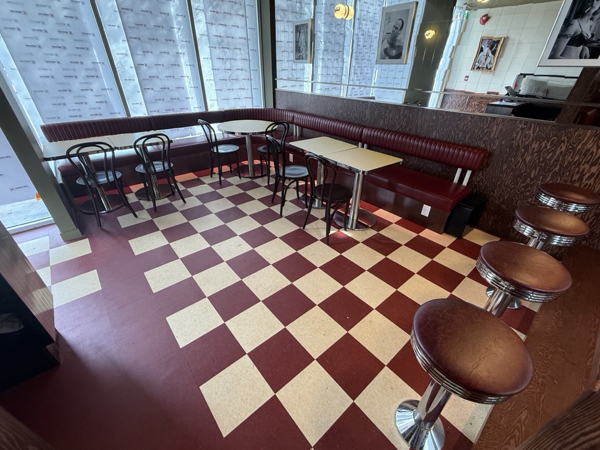 Burgundy diner banquette with bentwood chairs and swivel stools above a red checkerboard floor