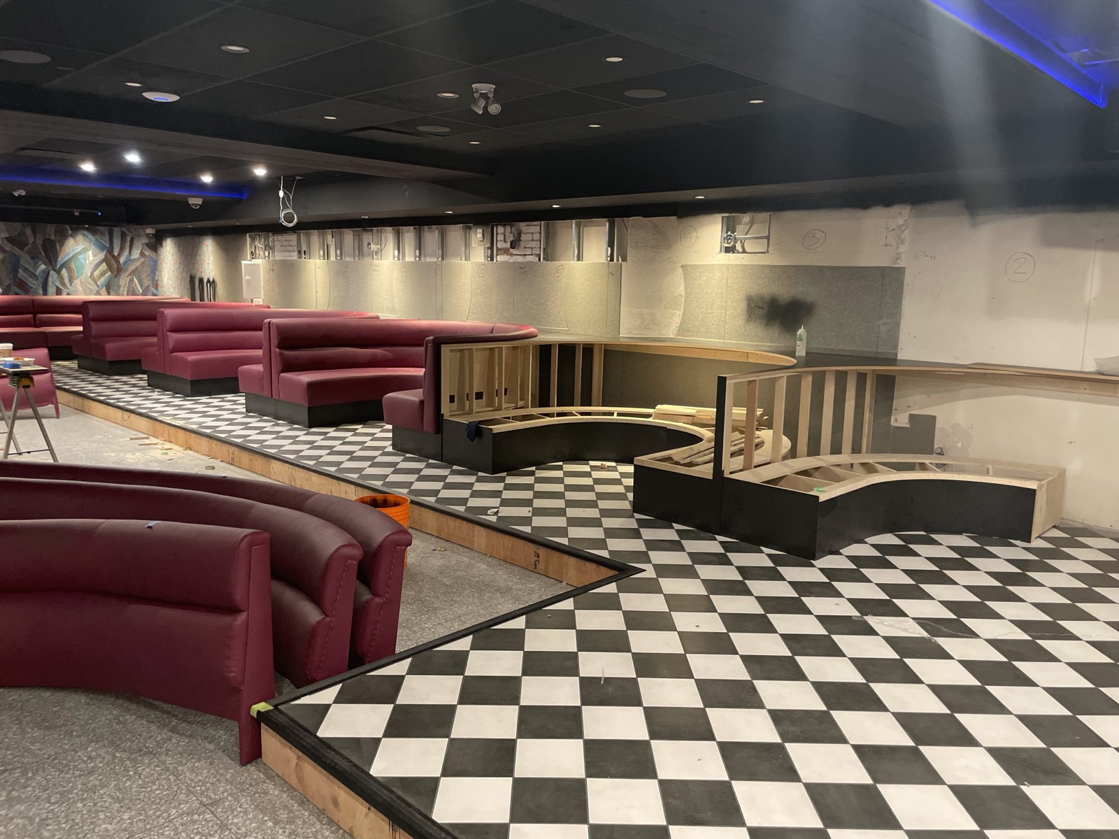 Burgundy vinyl booth seating installation in progress over a checkerboard floor