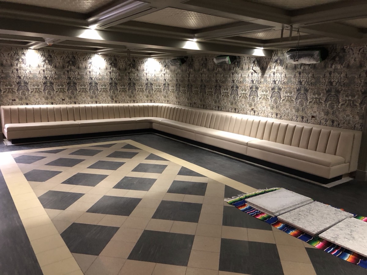 Cream fluted banquette wrapping a room with damask wallpaper and a checkerboard tile dance floor