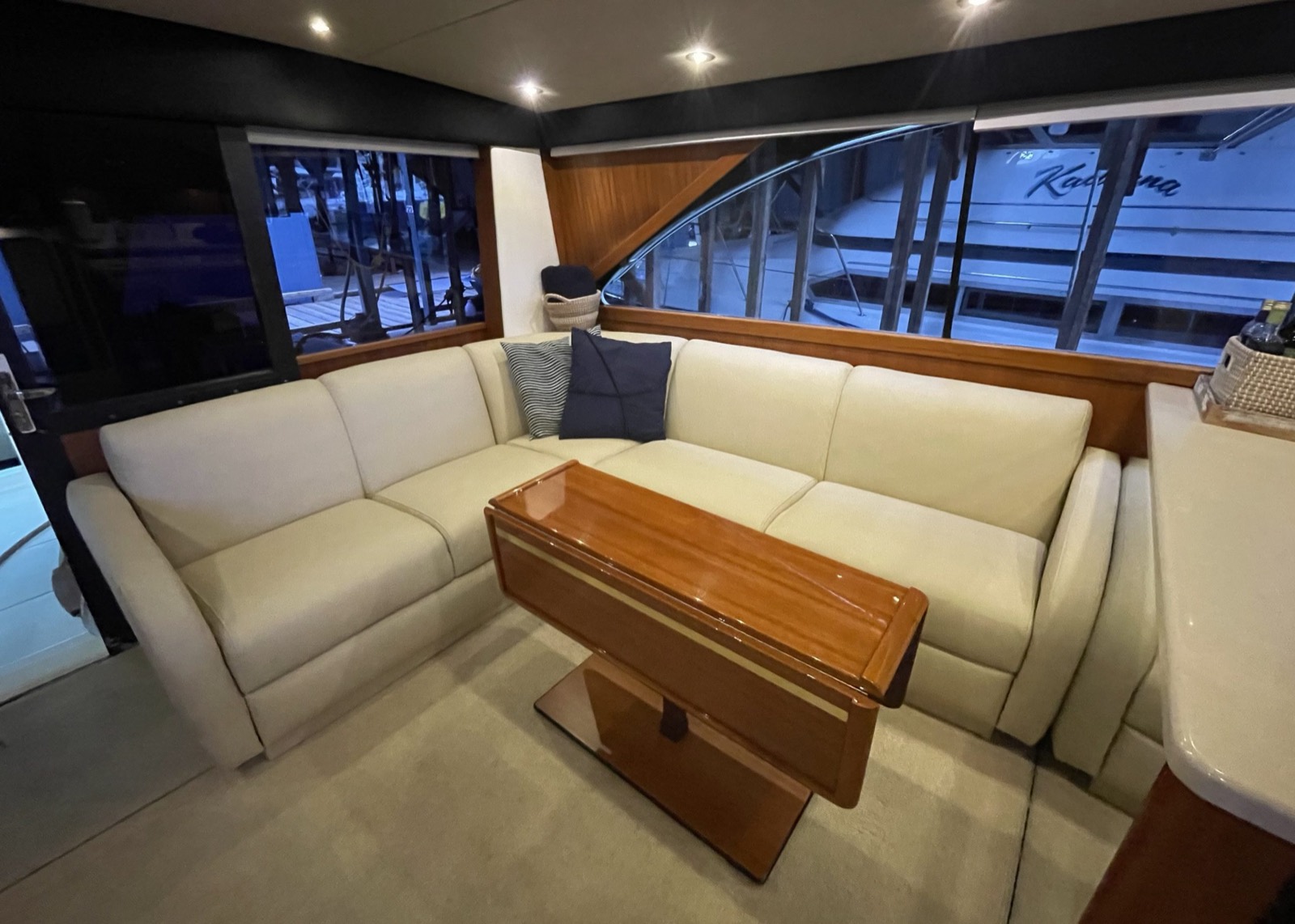 Cream leather boat cabin sectional seating with wood trim, marina view at dusk