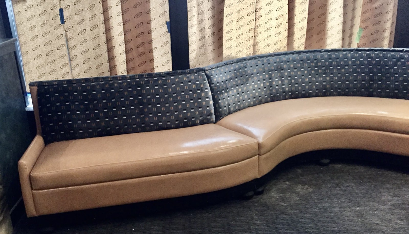 Curved caramel leather booth with patterned fabric backrest cushions and upholstery samples laid out