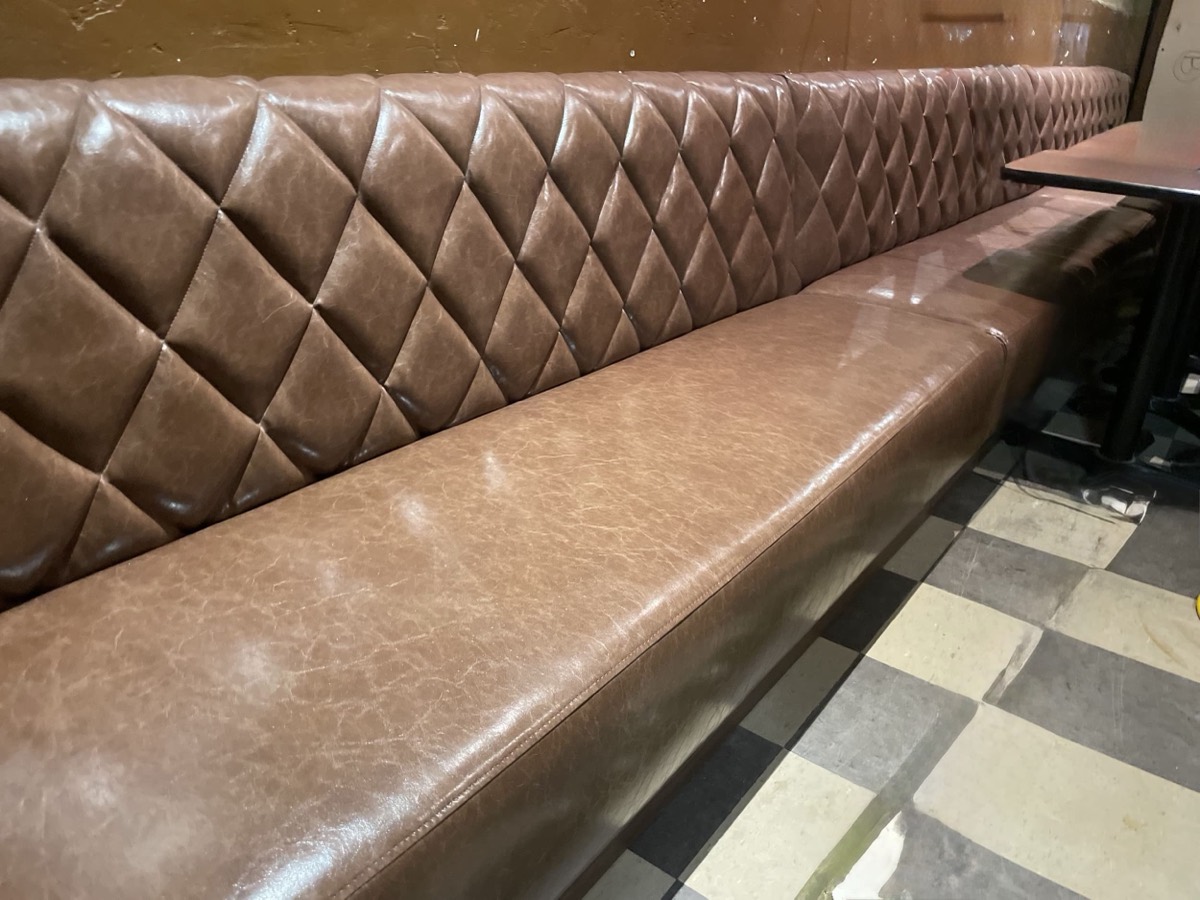 Brown diamond-tufted booth seating above a checkerboard floor