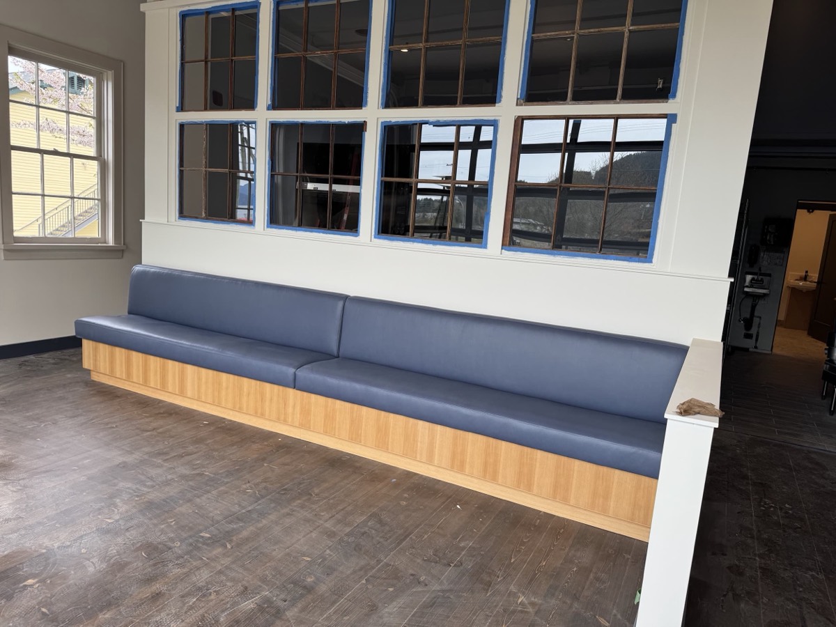 Navy vinyl bench with a light wood front panel below blue framed windows