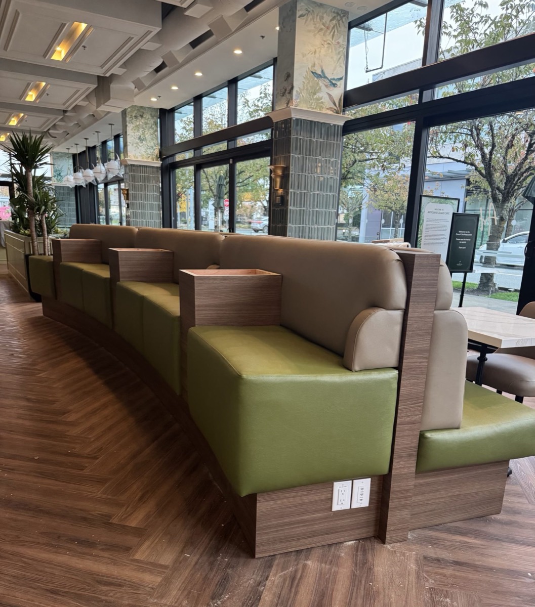 Curved restaurant banquette with olive green seats, tan backs and wood dividers on herringbone flooring
