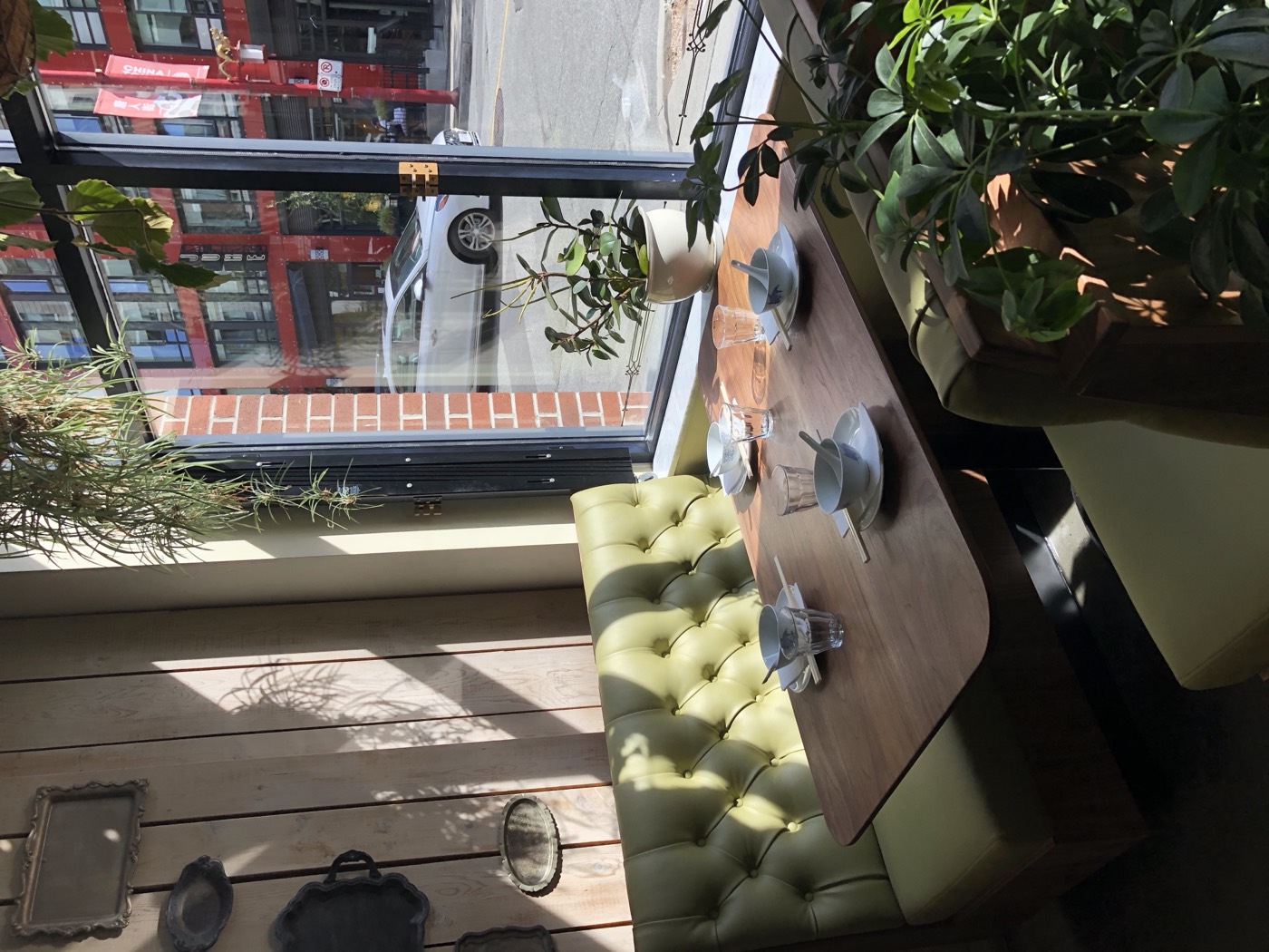 Sage green channel-tufted banquette seating beside a cafe till