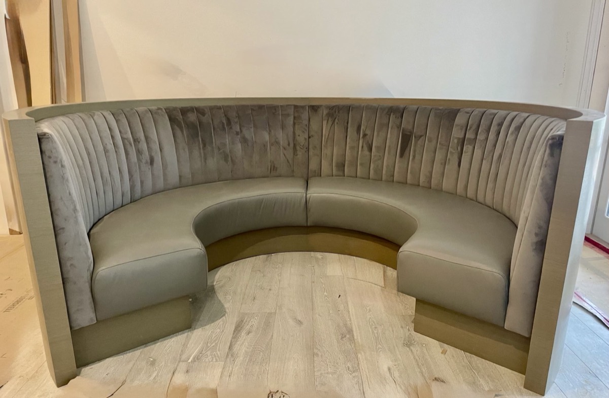 Semicircular booth with a grey velvet fluted back, taupe leather seats and a curved outer shell