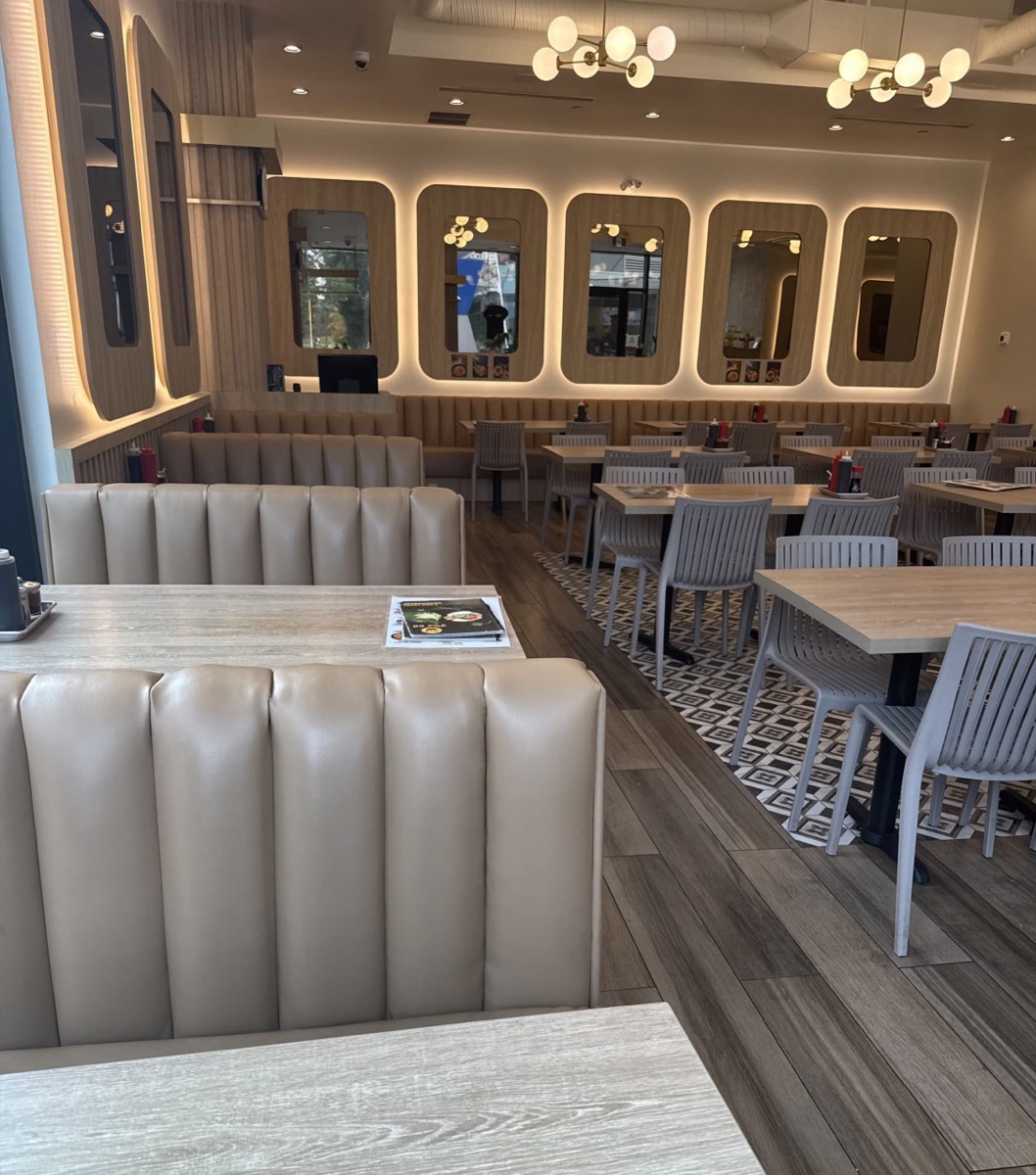 Taupe channel-tufted booths and light wood tables in a bright dining room with globe chandeliers