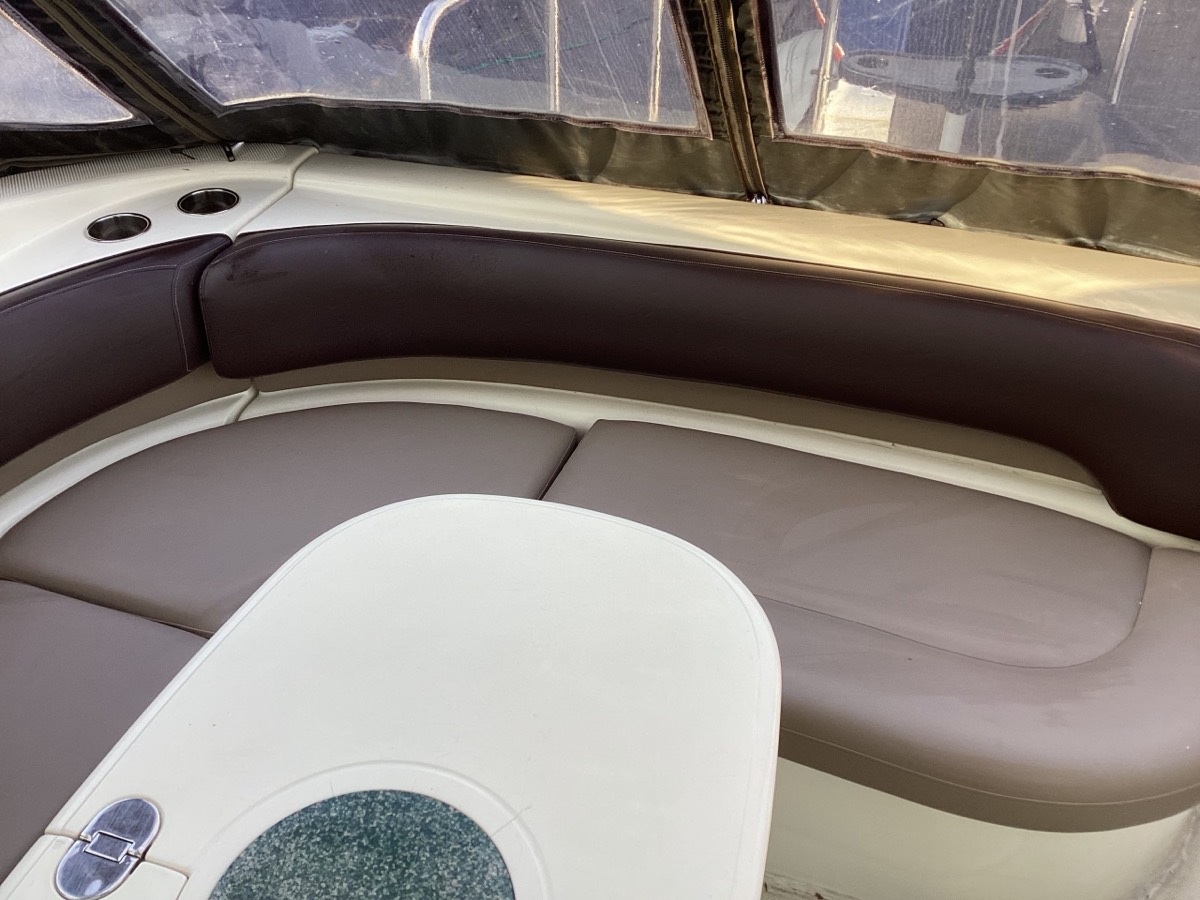 Curved boat bench cushion in taupe vinyl with burgundy trim inside a canvas enclosed cockpit